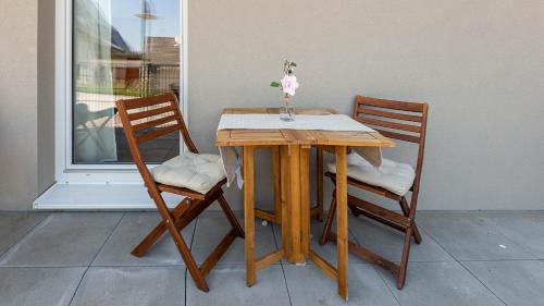 a wooden table with two chairs and a vase on it at Grimming Lodge Arnika in Tauplitz