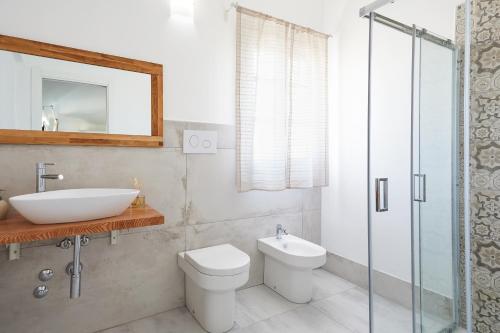 a bathroom with a sink and a toilet and a mirror at I Gufi Bed & Breakfast Marzamemi in Marzamemi