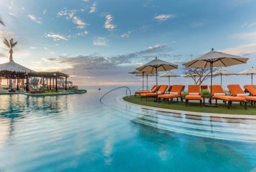 a swimming pool with orange chairs and umbrellas at Grand Solmar Land's End Resort & Spa in Cabo San Lucas