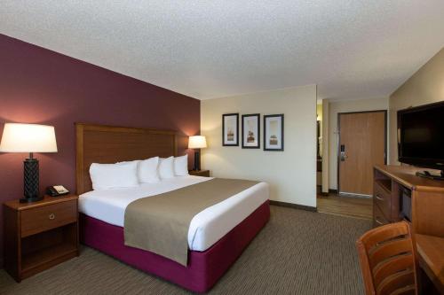 a hotel room with a large bed and a flat screen tv at AmericInn by Wyndham Merrill in Merrill