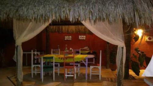 a dining room with a table and a thatch roof at Pousada A Vida é Bela in Águas Belas