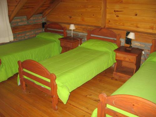 1 dormitorio con 2 camas verdes y suelo de madera en Cabañas Lorien en Esquel