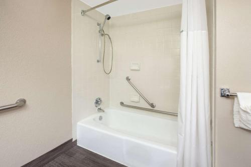 a bathroom with a white tub and a shower at Baymont by Wyndham Grand Rapids Near Downtown in Grand Rapids