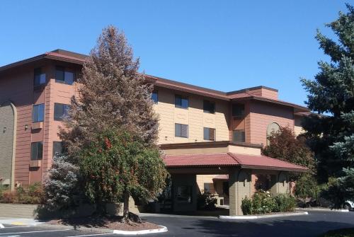 a large building with a tree in front of it at Baymont by Wyndham Yakima Riverfront in Yakima