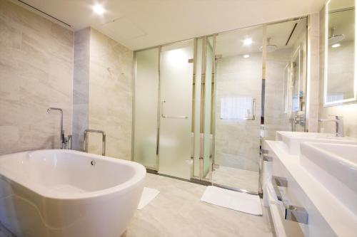 a bathroom with a tub and two sinks and a shower at Hotel Nikko Himeji in Himeji