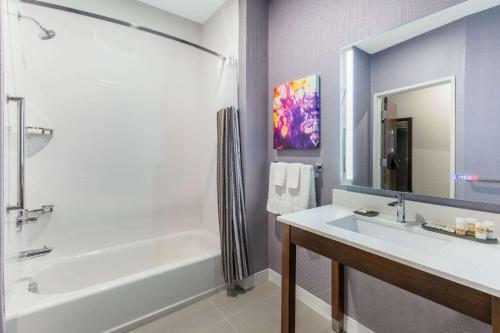 a bathroom with a white tub and a sink at La Quinta Inn & Suites by Wyndham Lewisville in Lewisville