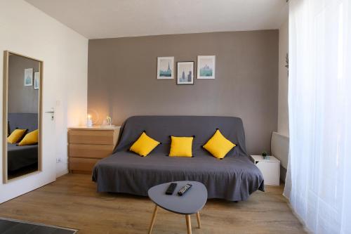 Un dormitorio con una cama con almohadas amarillas y una mesa. en expat renting - Le Sophia - Casino Barrière - Parking en Toulouse