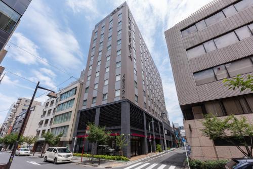 een hoog gebouw in een stadsstraat met een auto bij Hotel Kazusaya in Tokyo