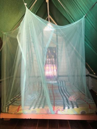 a bed with a net in a tent at Beach Shack Chalet - Garden View Aframe Small Unit in Tioman Island