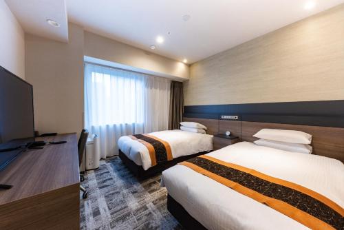 a hotel room with two beds and a flat screen tv at Hotel Kazusaya in Tokyo