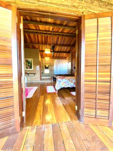 a living room with a bed and a wooden floor at Pousada Recanto da Siriema in Monte Alegre do Sul