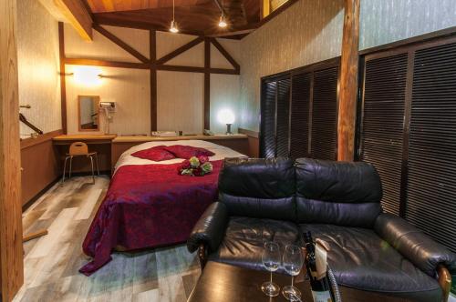 um quarto com uma cama e um sofá de couro em Hotel JuJu em Kurume