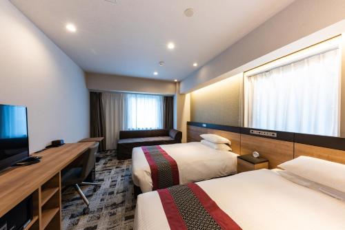 a hotel room with two beds and a flat screen tv at Hotel Kazusaya in Tokyo