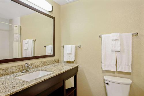 a bathroom with a sink and a toilet and a mirror at La Quinta by Wyndham Gillette in Gillette