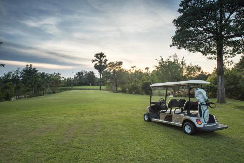 a golf cart parked in a field of grass at Baan Suan Khun Ta and Golf Resort in Ubon Ratchathani