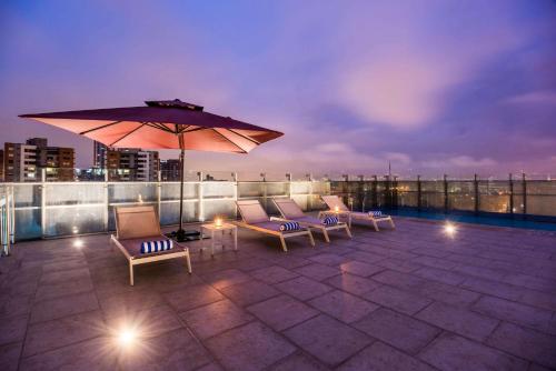 a patio with chairs and an umbrella on a roof at La Quinta by Wyndham Medellin in Medellín