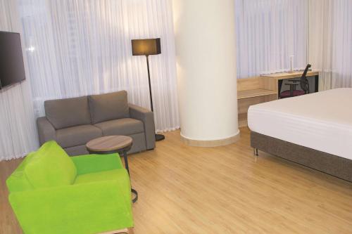 a bedroom with a bed and a couch and a chair at La Quinta by Wyndham Medellin in Medellín