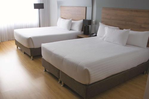a hotel room with two beds and a television at La Quinta by Wyndham Medellin in Medellín