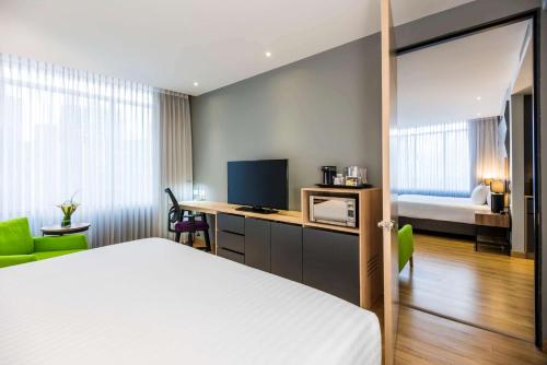 a bedroom with a bed and a desk with a television at La Quinta by Wyndham Medellin in Medellín