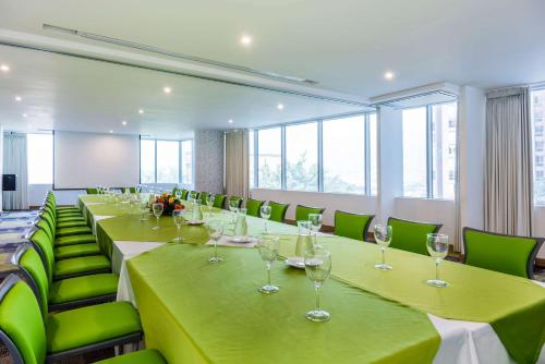 a conference room with long tables and green chairs at La Quinta by Wyndham Medellin in Medellín