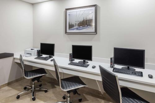 a office with three computers on a desk with chairs at Ramada by Wyndham Revelstoke in Revelstoke