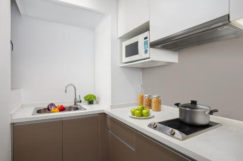a kitchen with a sink and a stove and a microwave at Citadines Xinghai Suzhou in Suzhou