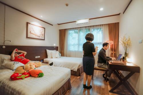 a woman standing in a hotel room with two beds at Thang Long Opera Hotel in Hanoi