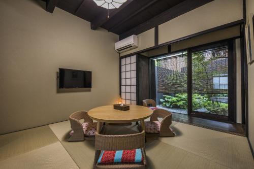a room with a table and chairs and a tv at Shiki Homes KYOKA in Kyoto