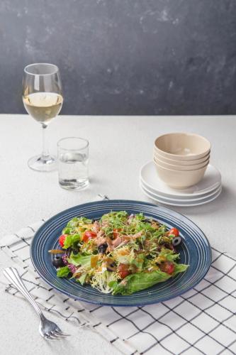 a plate of salad on a table with a glass of wine at Thang Long Opera Hotel in Hanoi