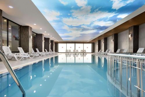 a pool in a hotel with chairs and a sky at Ramada By Wyndham Giresun Piraziz in Piraziz