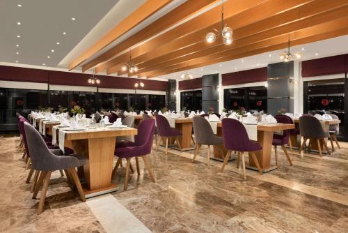 a dining room with tables and purple chairs at Ramada By Wyndham Giresun Piraziz in Piraziz