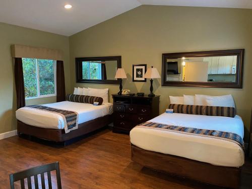 a bedroom with two beds and a mirror at Sea Breeze Inn - Pacific Grove in Pacific Grove