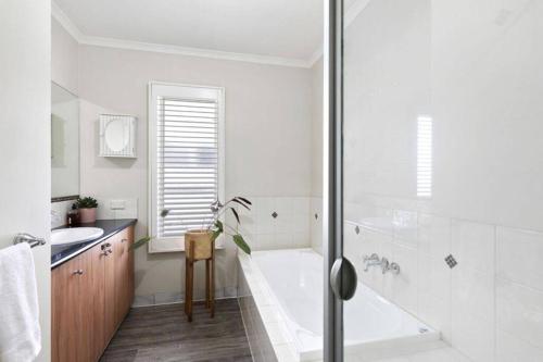 ein weißes Badezimmer mit einer Badewanne und einem Waschbecken in der Unterkunft Jan Juc Ocean Views - Pet friendly in Torquay