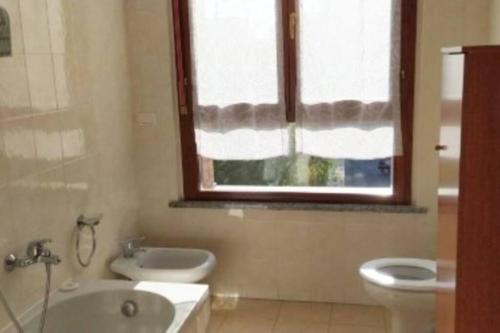 een badkamer met een wastafel, een toilet en een raam bij LA SISTEMAZIONE BRILLANTINO TITANIUM in Rozzano