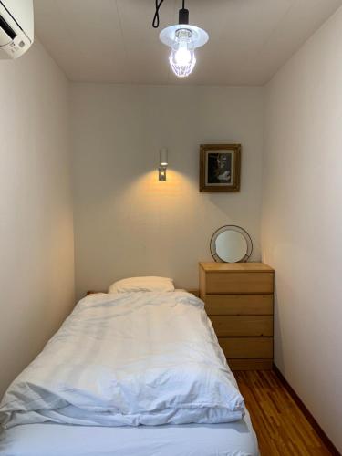 a bedroom with a white bed and a dresser at Children's cafe B&B Kimie in Kamakura