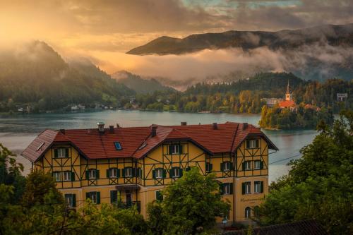 a yellow house with a view of a lake and mountains at Hotel Triglav in Bled