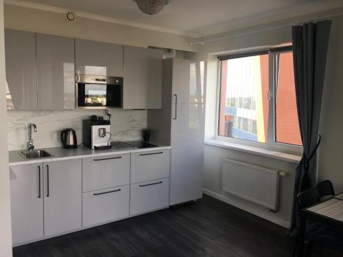 a kitchen with white cabinets and a window at City Apartment in Klaipėda