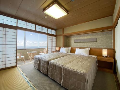 a bedroom with a large bed and a large window at Mikawa Bay Hills Hotel in Nishio