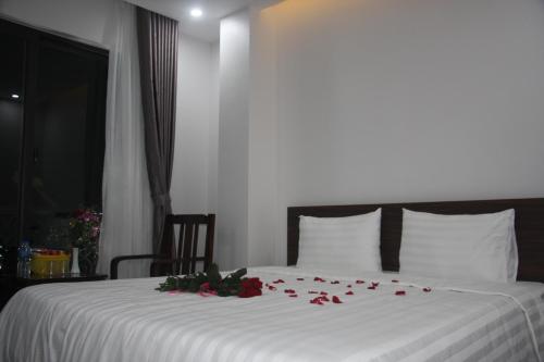 a bedroom with a white bed with roses on it at SUN HOTEL & APARTMENT in Bắc Ninh