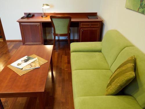 a living room with a green couch and a table at Hradná stráž Hotel&Apartments s privátnym wellness in Topoľčianky