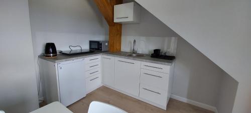 a white kitchen with a sink and a staircase at Pokoje Gościnne Cztery Wiatry in Frombork