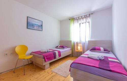 a bedroom with two beds and a yellow chair at Apartments Ivka in Omiš