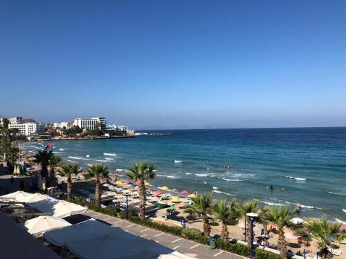 a beach with umbrellas and palm trees and the ocean at Ladies Beach Hotel in Kuşadası