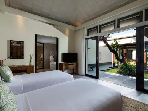 Avani Seminyak Bali Resort في سمينياك: غرفة نوم بسريرين وتلفزيون ونافذة