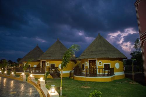 a row of cottages with thatched roofs at night at Sun Hotel and Resort, Mount Abu in Ābu Road