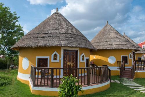 a small yellow house with a thatched roof at Sun Hotel and Resort, Mount Abu in Ābu Road