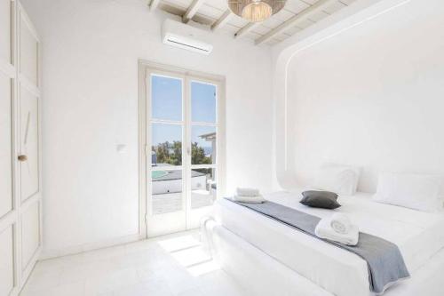Un dormitorio blanco con una cama y una ventana grande. en Villa Esencia, en Agios Ioannis Mykonos