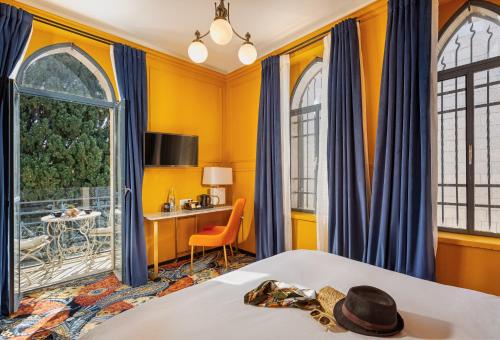 a bedroom with yellow walls and blue drapes at Villa Brown Moshava - a member of Brown Hotels in Jerusalem