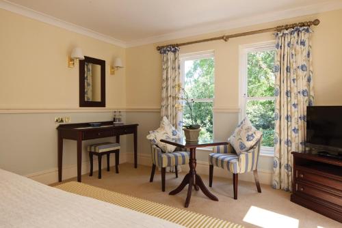 a bedroom with a bed and a desk and a window at The Dower House Hotel in Woodhall Spa