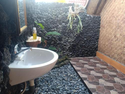 y baño con ducha de roca con lavabo. en Lakeside Log Cabins, en Kintamani